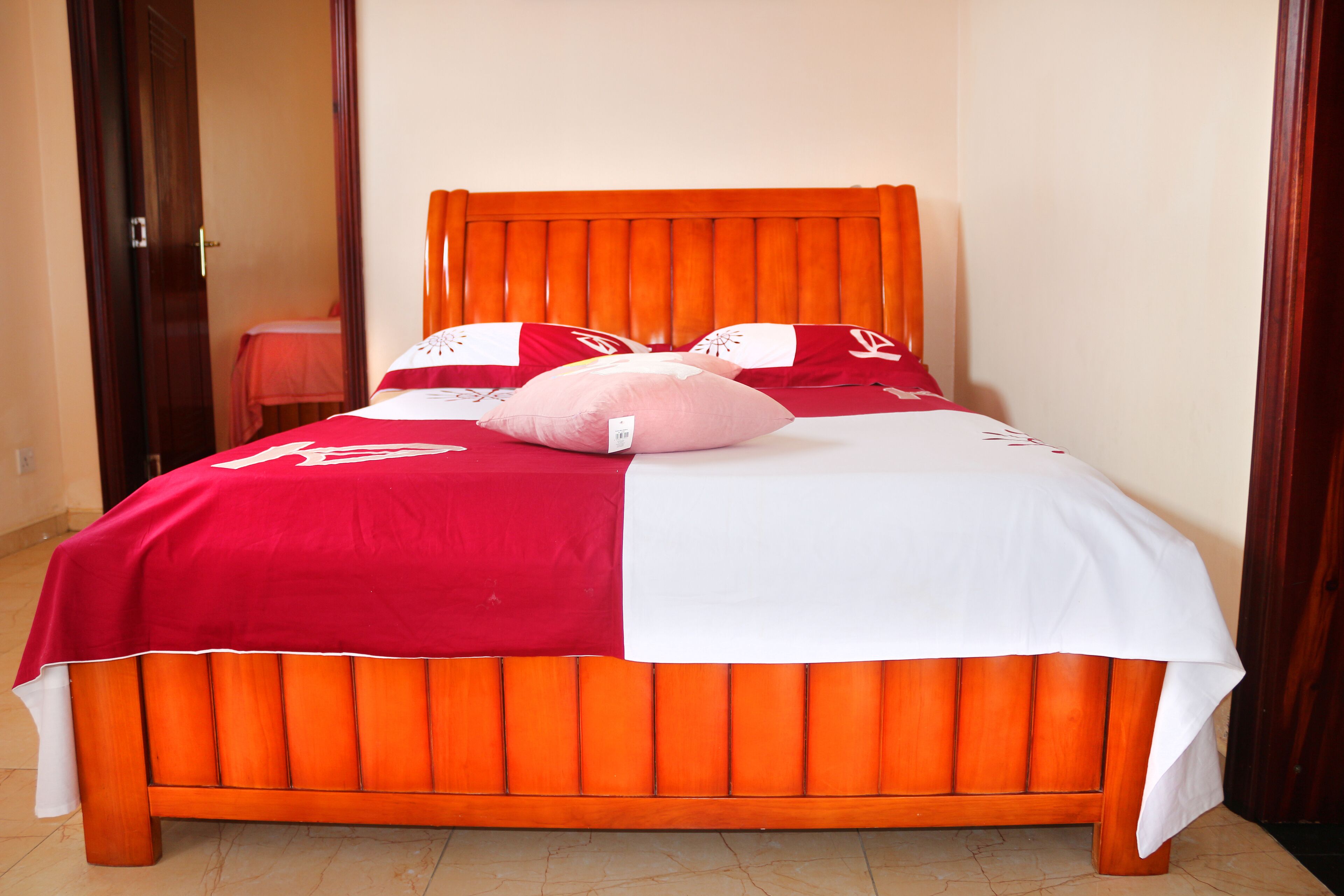 A bed with an orange headboard and a red and white bedspread.