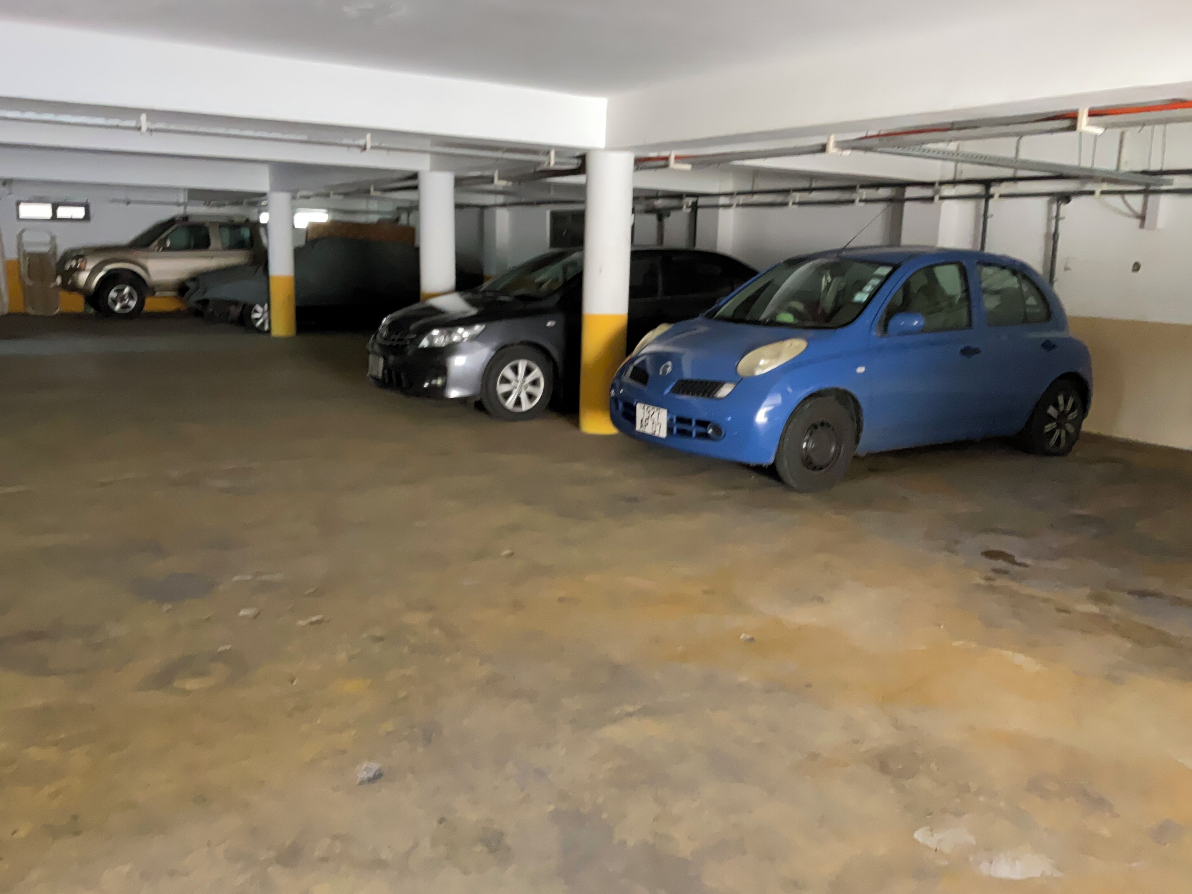 Un estacionamiento con tres coches aparcados en fila.