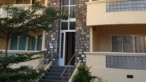 Un hotel de varios pisos con una entrada central flanqueada por pilares de piedra, varios balcones y una escalera que conduce a la entrada.