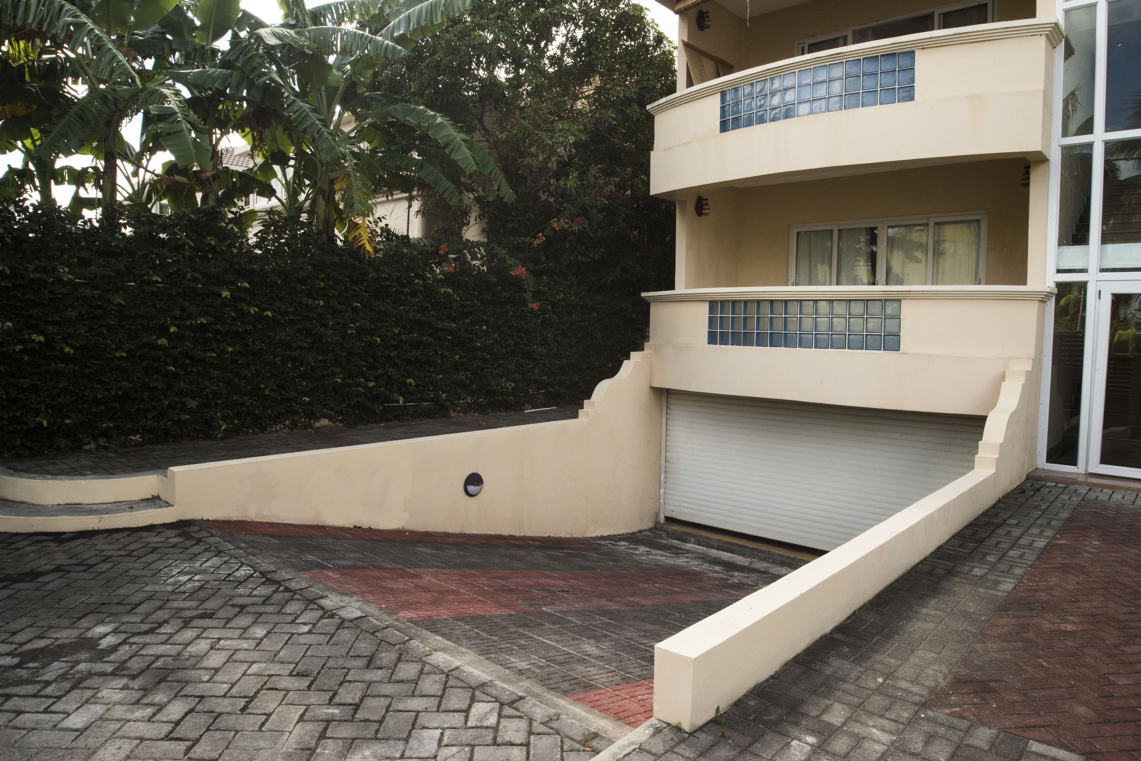 Un edificio de varios pisos con techo plano, puerta de garaje y entrada pavimentada.