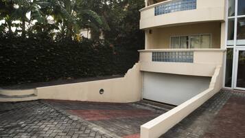 Un edificio de varios pisos con techo plano, puerta de garaje y entrada pavimentada.
