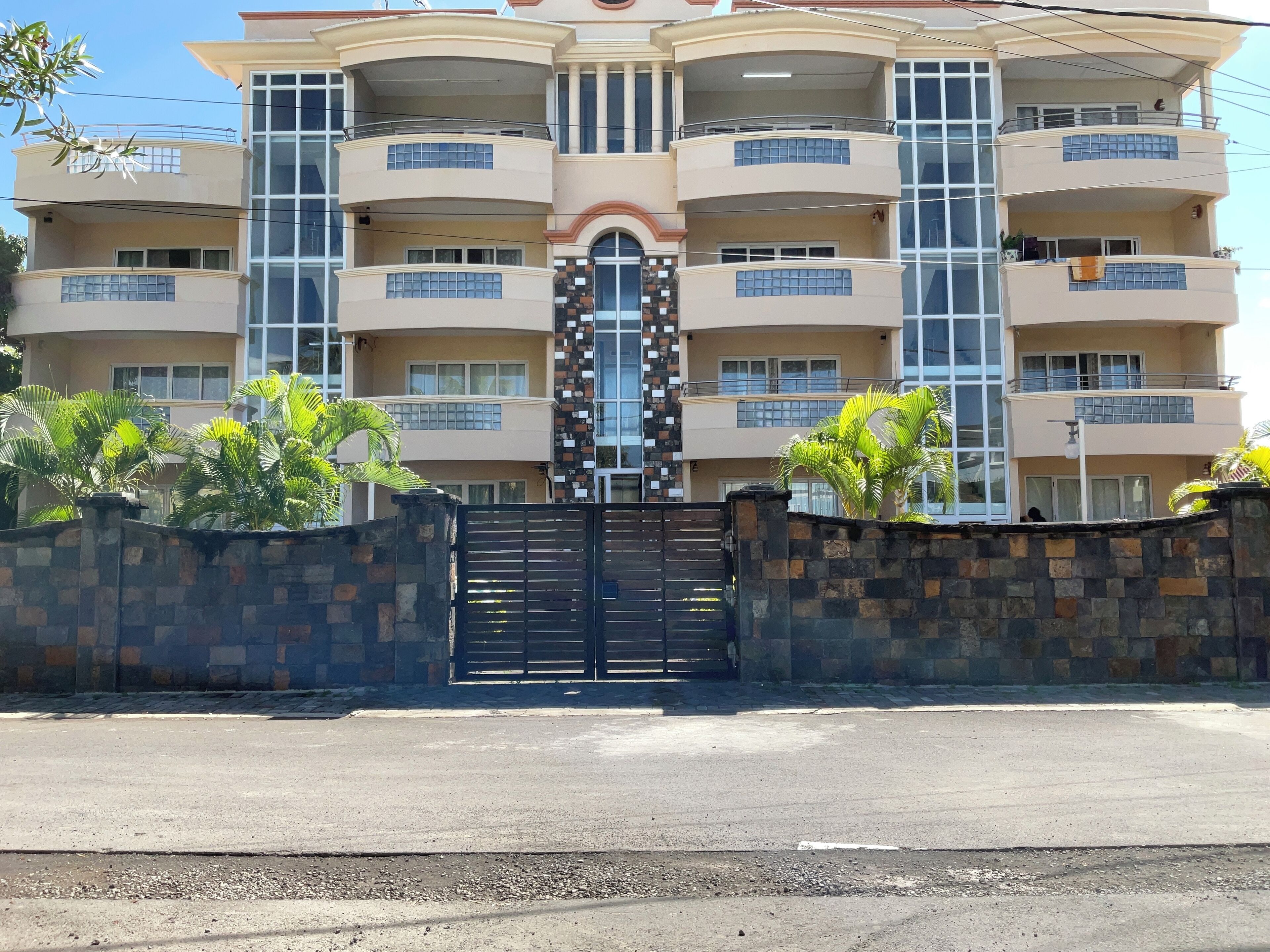 A multi-story building with balconies and a gated entrance.