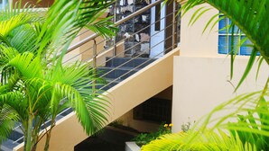 Una escalera con barandilla metálica, rodeada de exuberantes plantas de palmera.