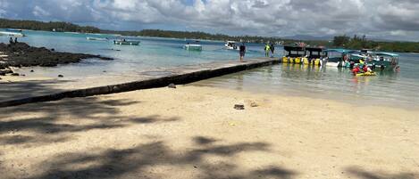 A beach with boats docked, a sandy shore, and a clear sky.