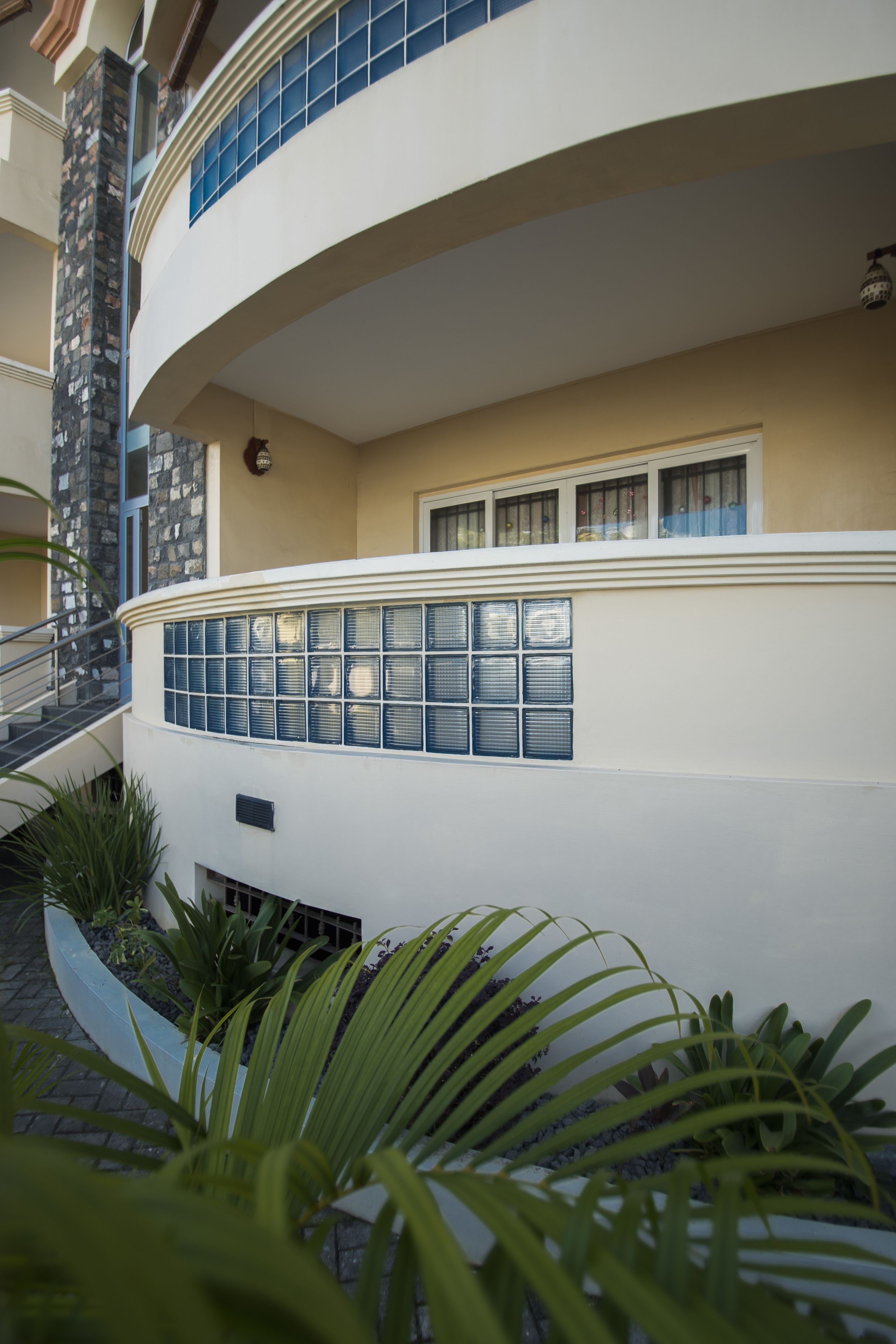 Un edificio de varios pisos con balcón curvo, fachada de piedra y una serie de ventanas.