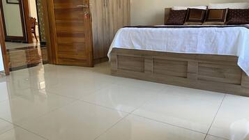 Un dormitorio con estructura de cama de madera, colcha blanca y armario de madera.