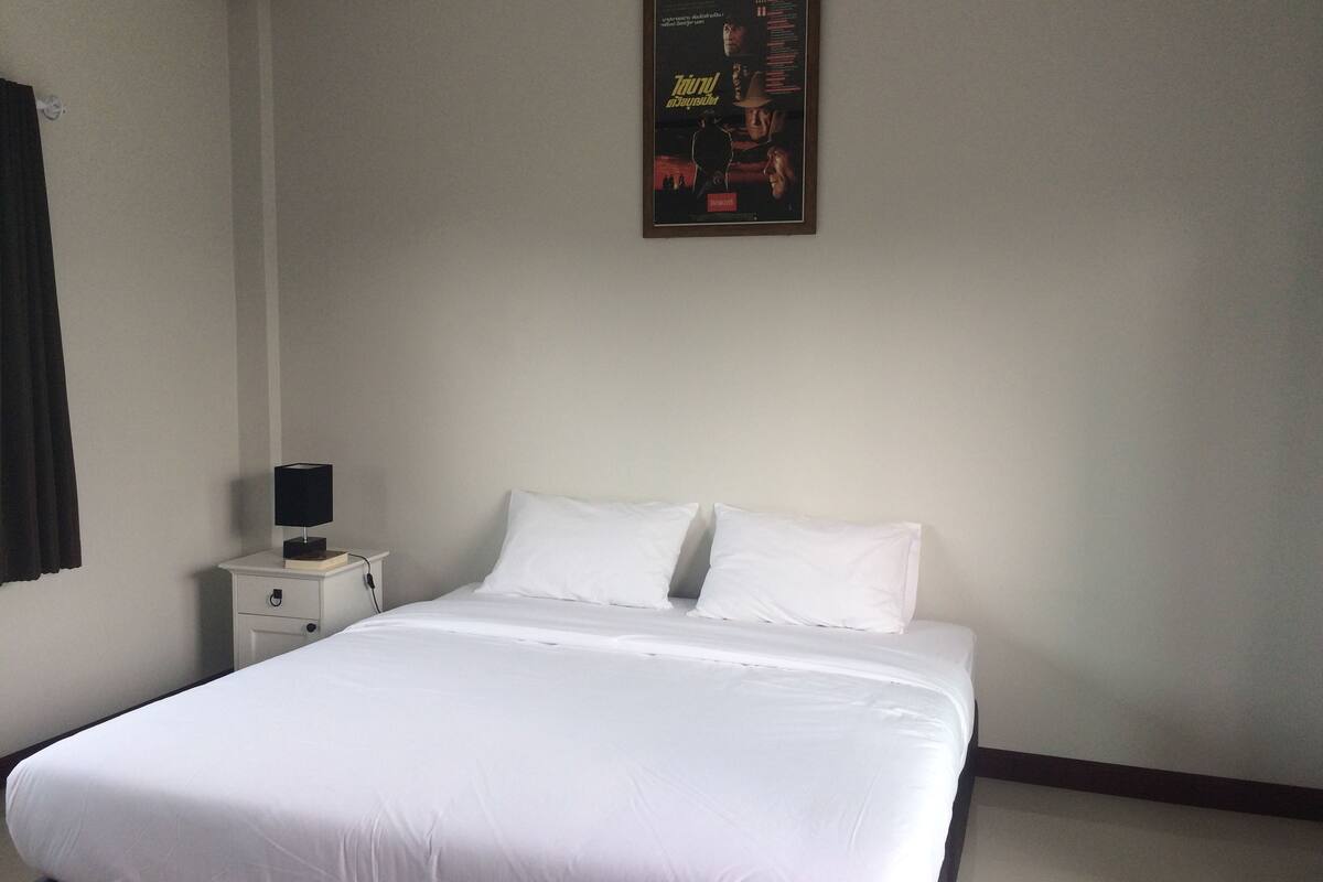 A neatly made bed with white linens in a hotel room.