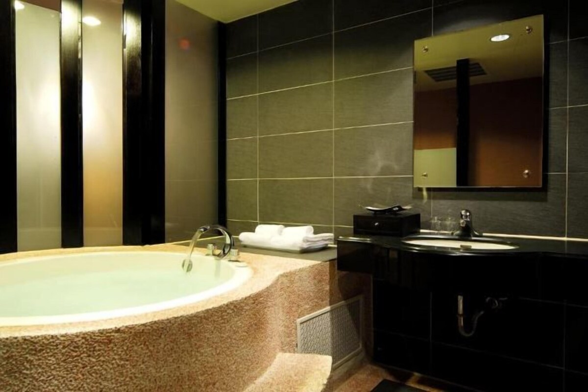A modern bathroom with a freestanding bathtub, a vanity with a mirror, and a towel rack.