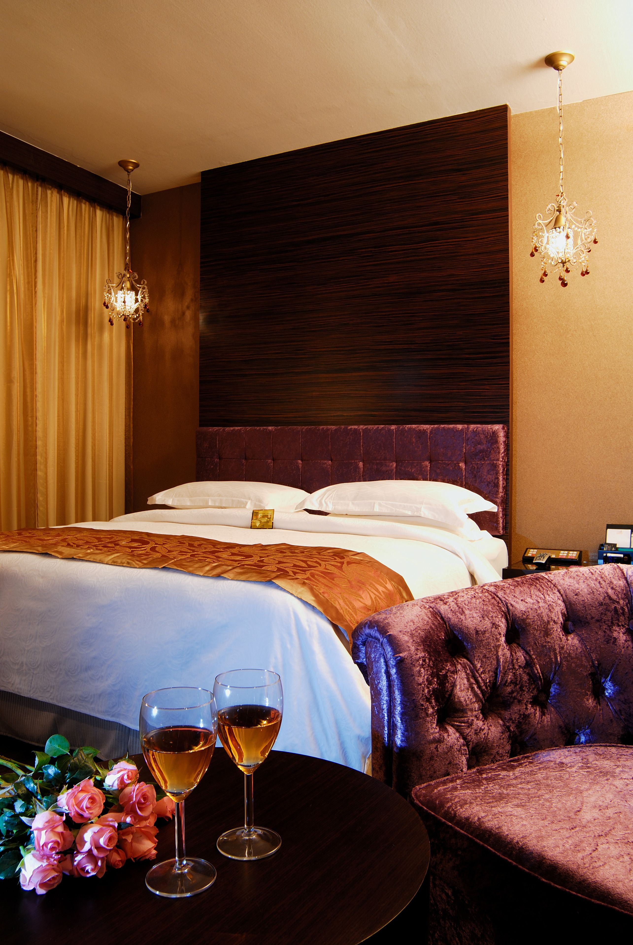 A hotel room with a large bed, two bedside tables, a round coffee table, and a plush armchair.