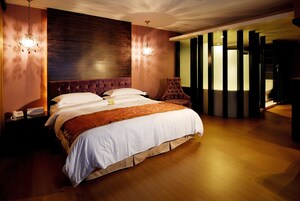 Ampia camera da letto con un letto grande, una testiera in legno e un moderno lampadario.