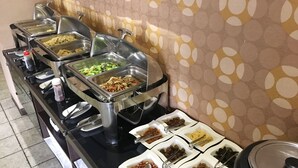 A buffet with various food items in metal containers and bowls, a water dispenser, and a large pot on the right. - The Riverside Hotel & Motel (Kaohsiung)