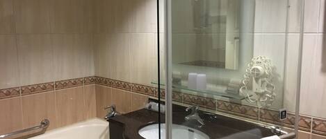 A bathroom with a bathtub, a sink, and a glass shower enclosure.