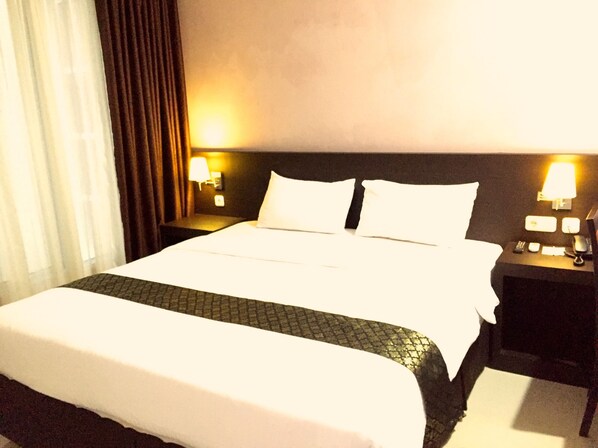 Une chambre d’hôtel avec un grand lit, deux tables de chevet avec des lampes et une tête de lit.