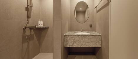 Un baño moderno con lavamanos de granito, ducha de mano y espejo montado en la pared.