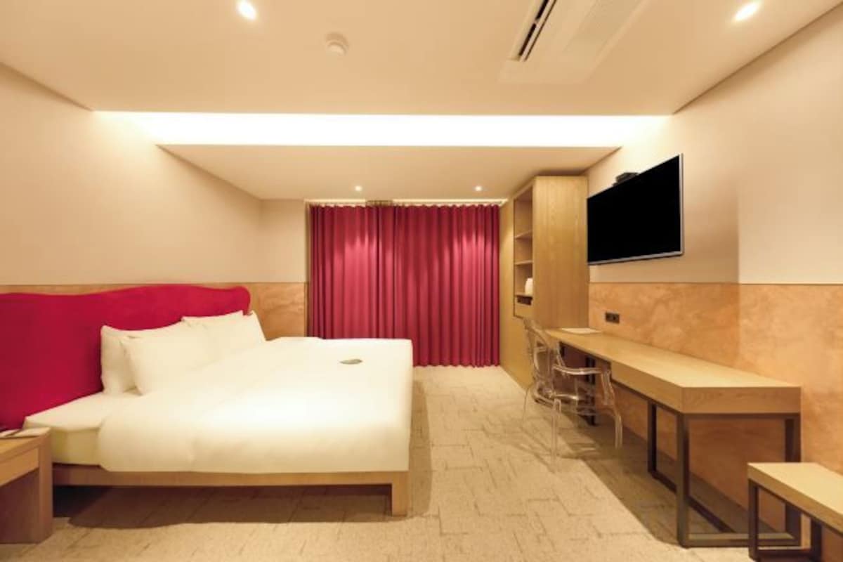 Una habitación de hotel moderna con una cama, un escritorio y un televisor montado en la pared.