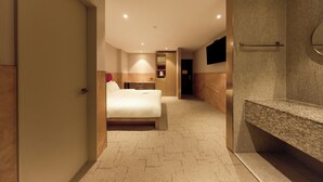 A modern hotel room with a bed, a vanity with a granite countertop, and a large mirror. - Capace Hotel (Seoul)