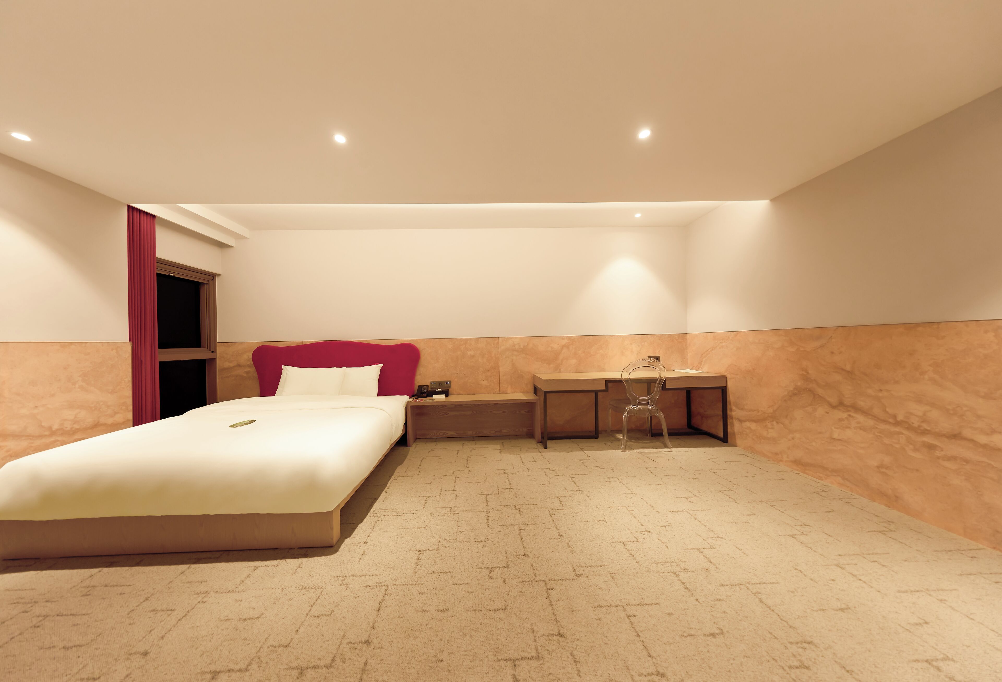 A modern hotel room with a bed, a desk, and a chair.