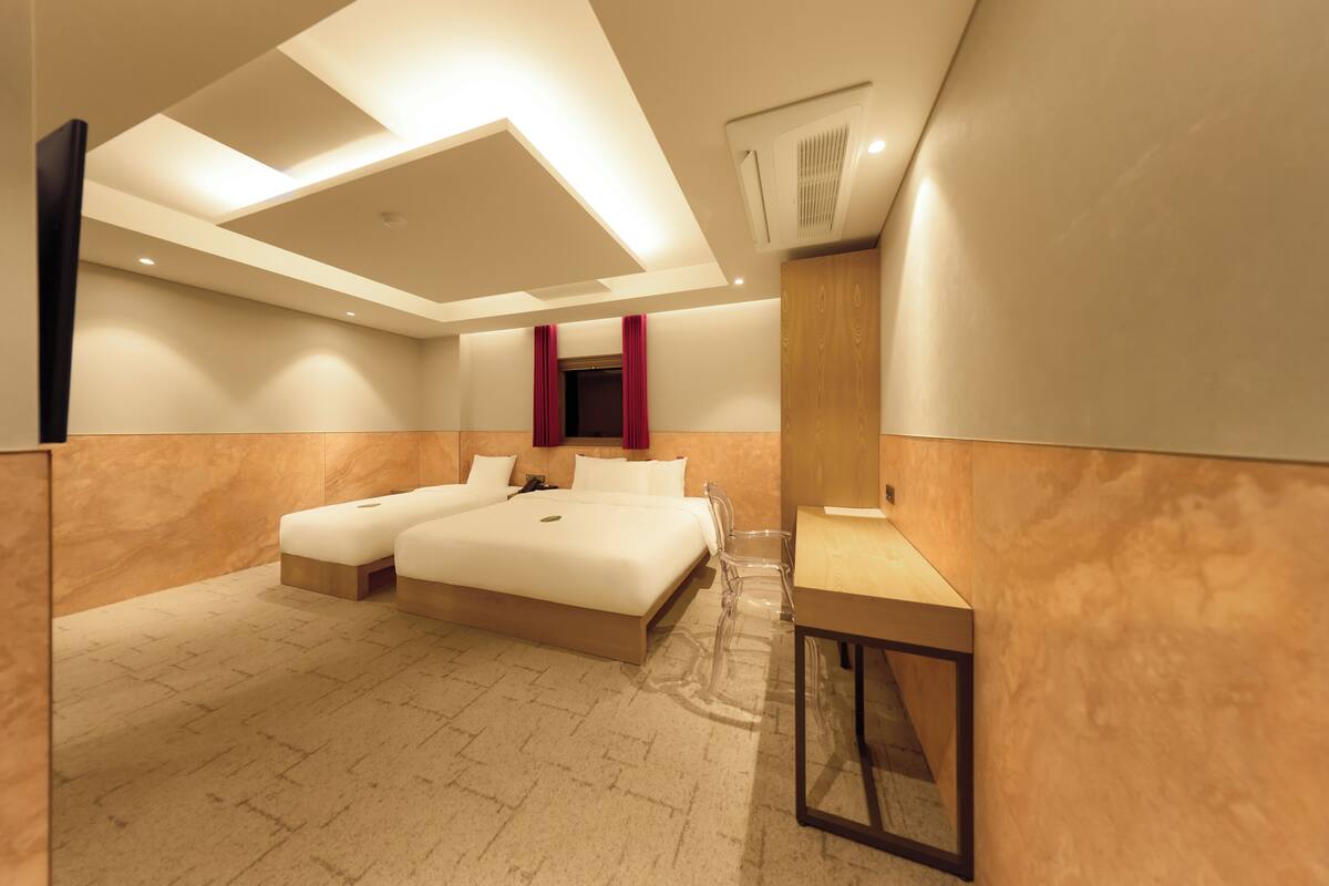 A modern hotel room with a large bed, a desk, and a mirror.