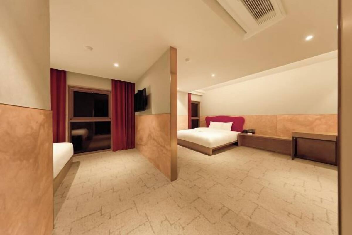 A hotel room with a bed, a desk, a TV, and a window with curtains.