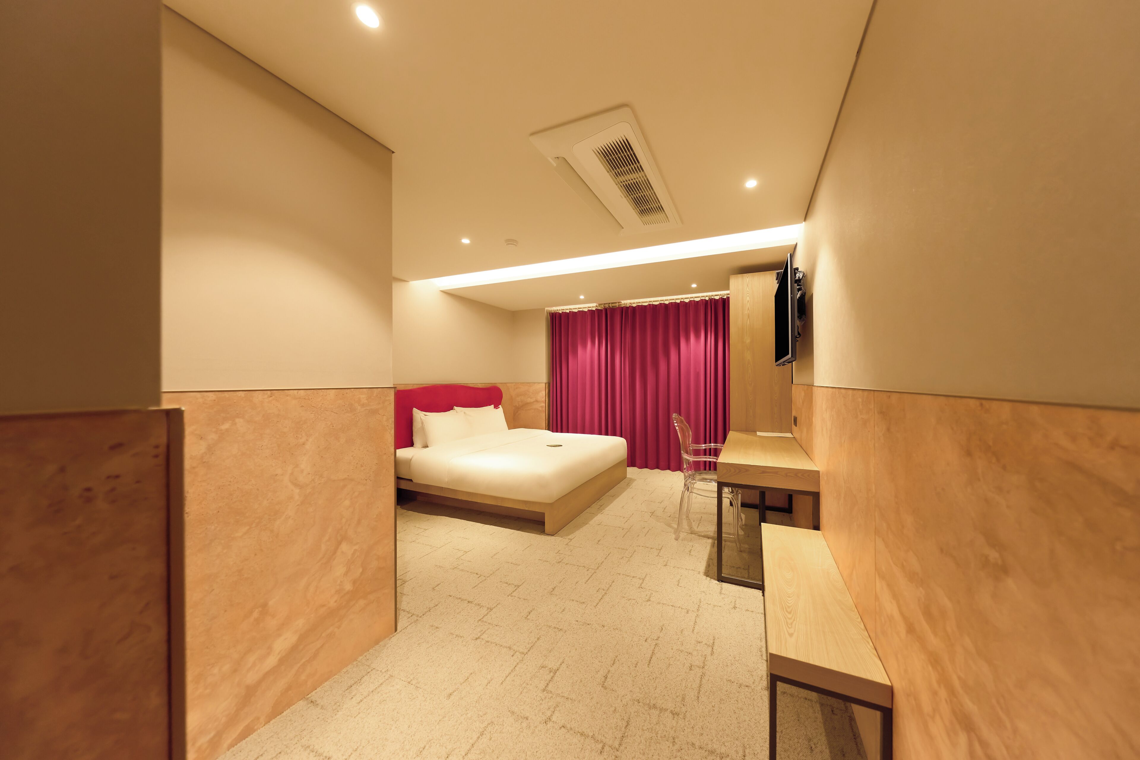 A modern hotel room with a bed, a desk, and a shower area.