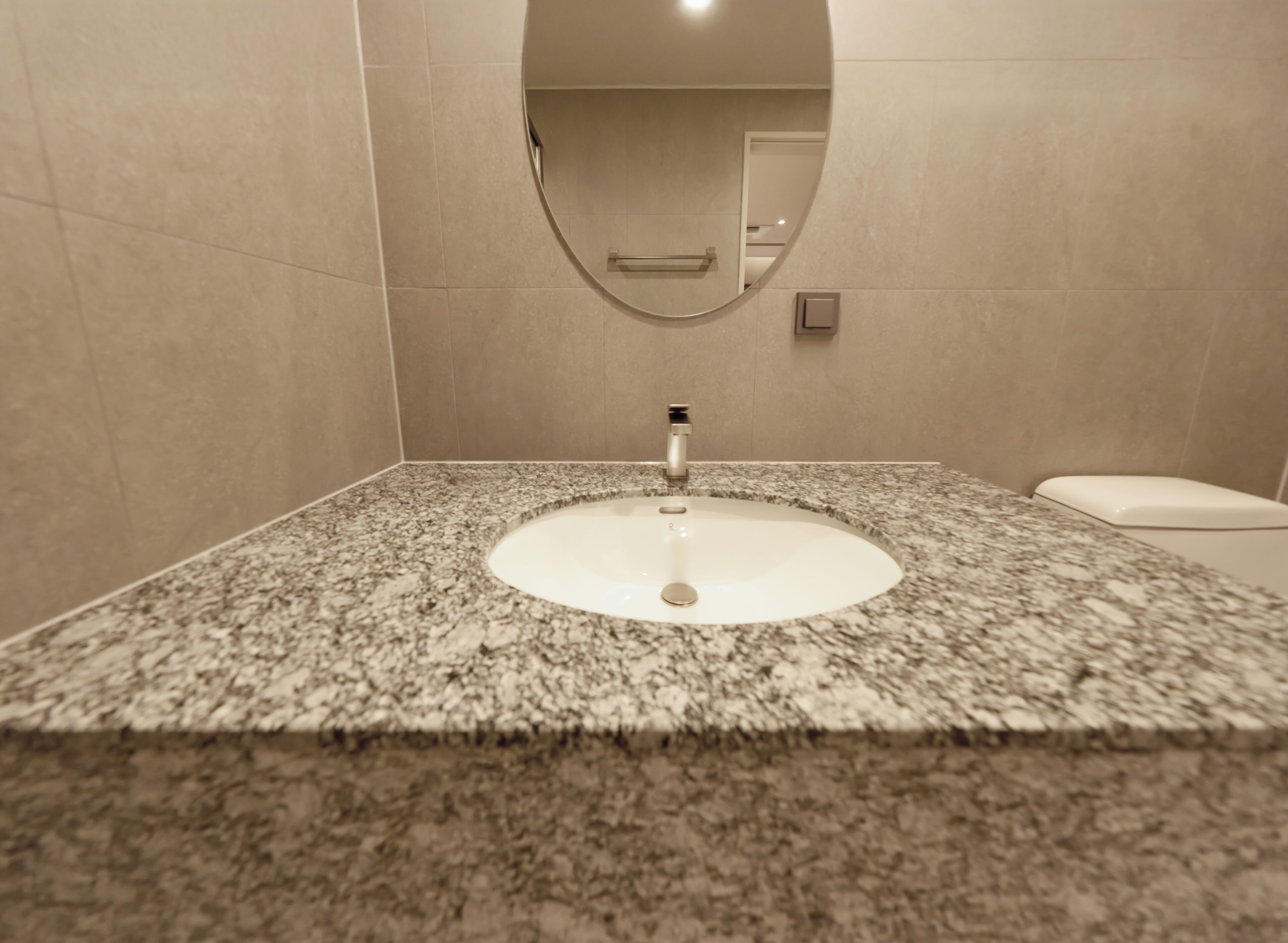 A bathroom with a granite countertop, a white sink, and a toilet.