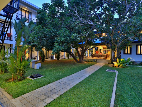 A well-maintained courtyard with a paved walkway, surrounded by lush greenery and trees.