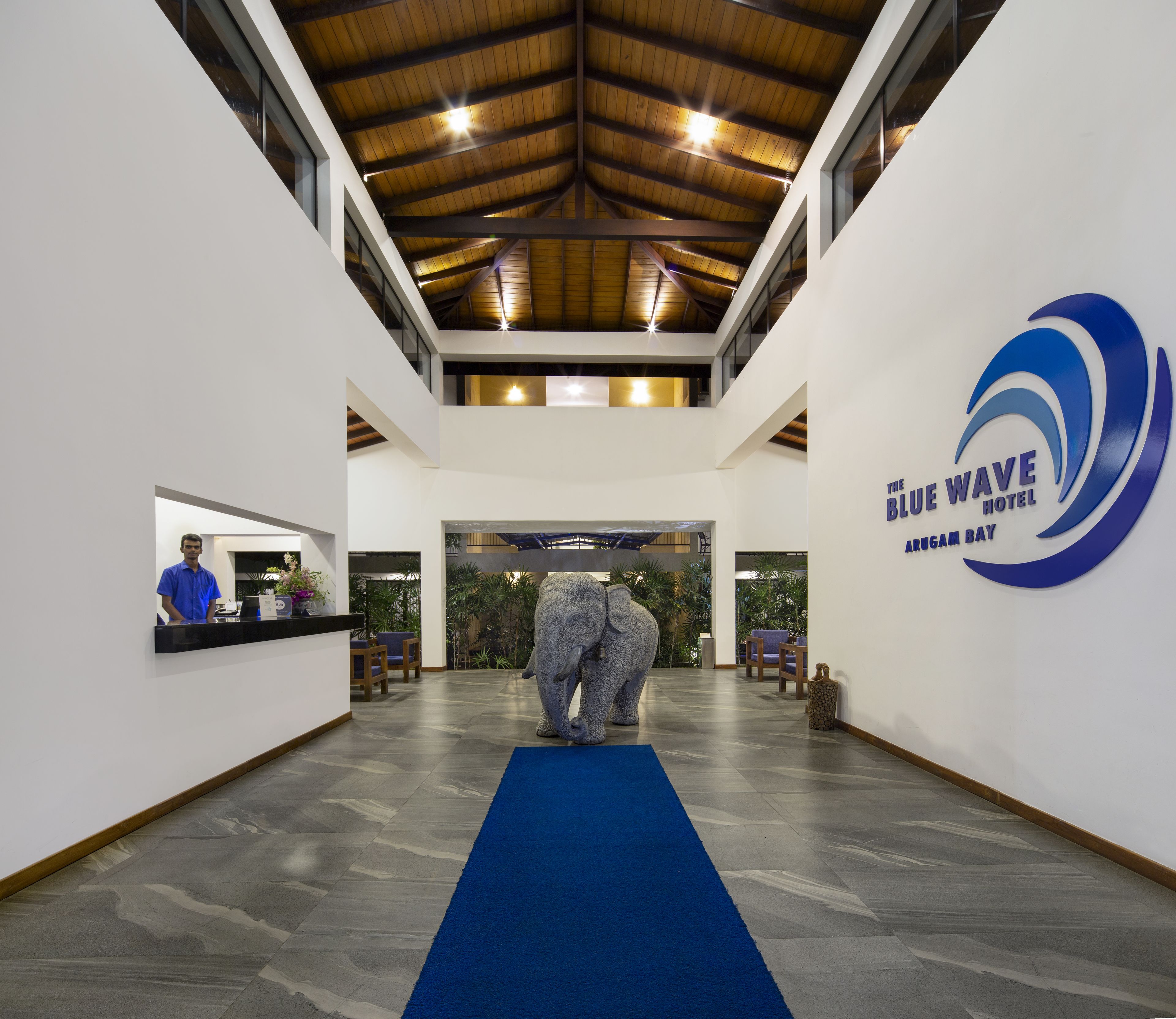 A reception area with a blue carpet, a receptionist, and a large elephant statue.