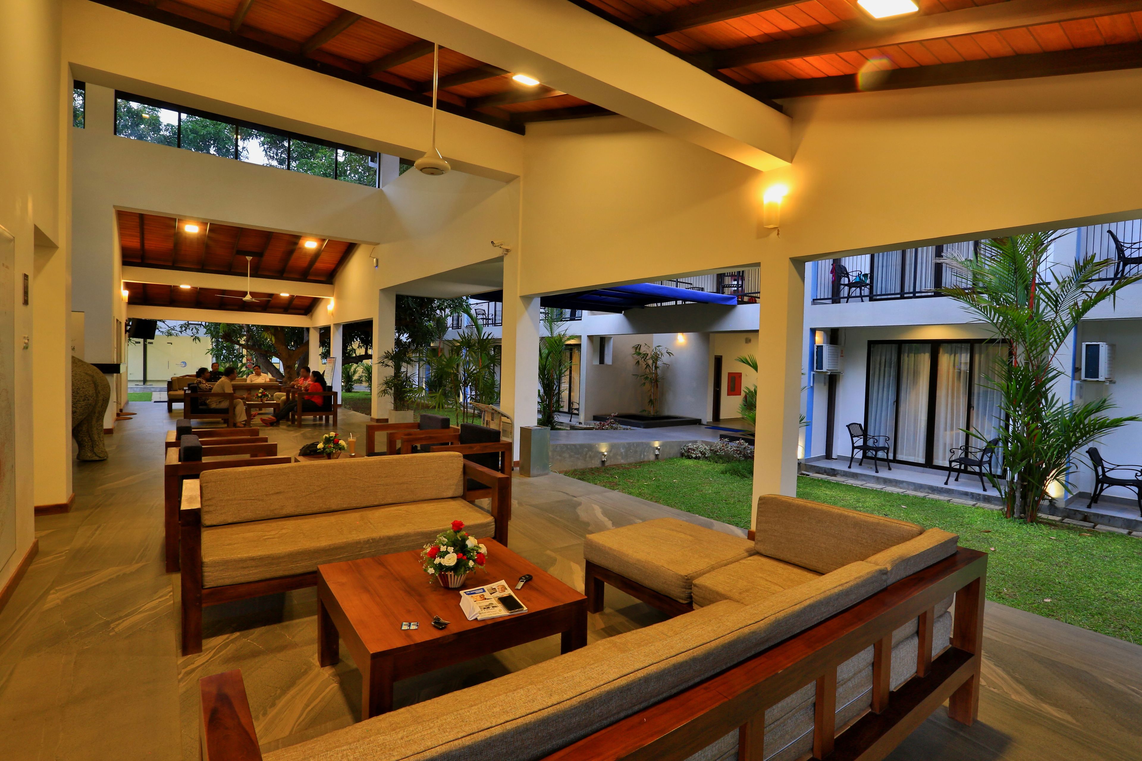 A spacious indoor area with multiple seating arrangements, a central table with a vase of flowers, and a view of the outdoor space.