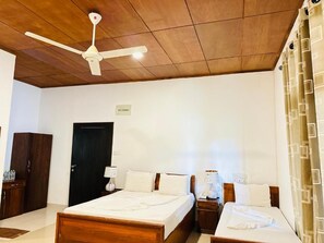 A hotel room with a wooden ceiling, two beds, a wardrobe, a desk, and a nightstand. - Gamodh Citadel Resort (Anuradhapura)