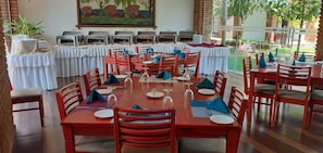 A dining area with multiple tables set for guests, each with plates, cutlery, and wine glasses. - Gamodh Citadel Resort (Anuradhapura)