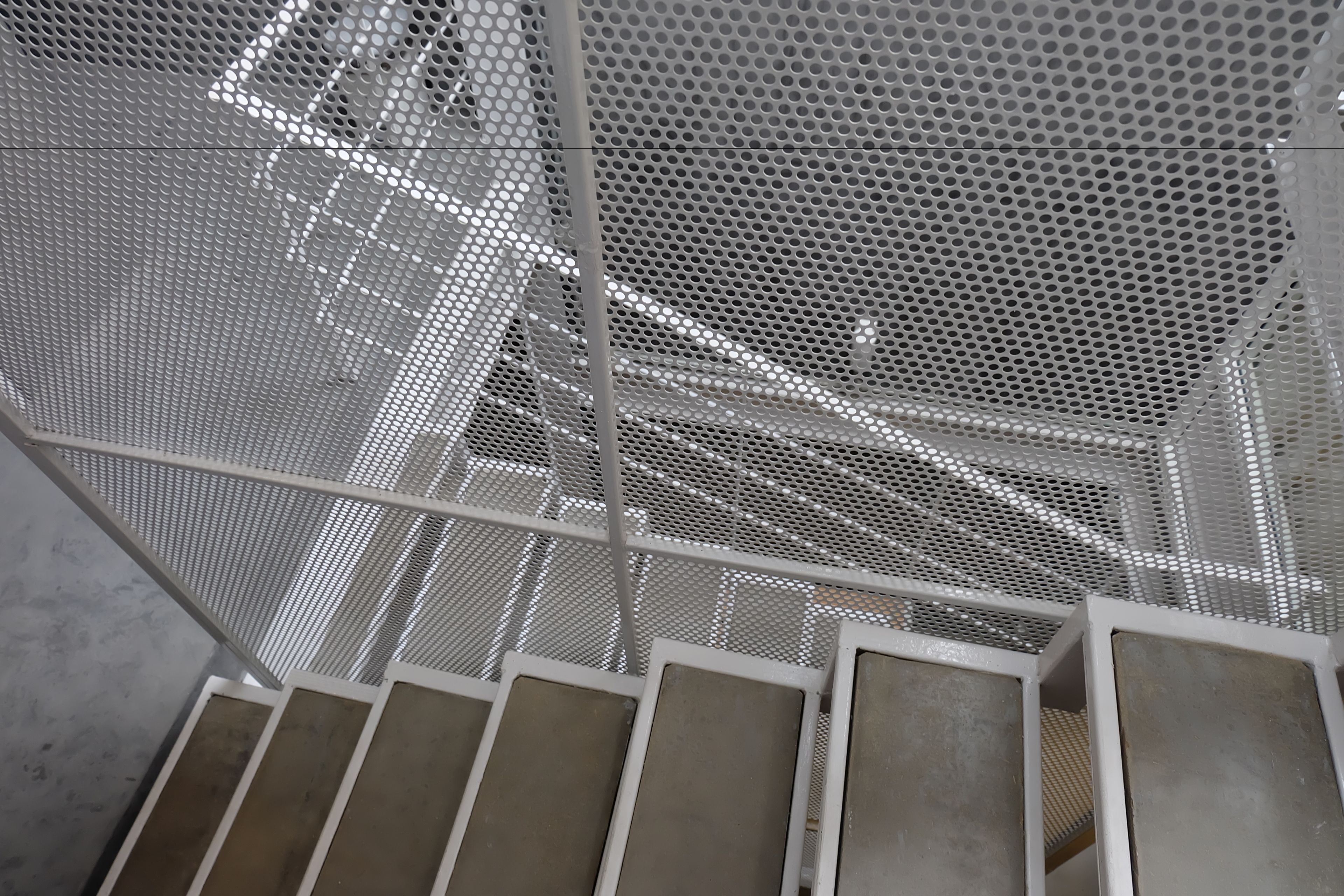 A metal staircase with a perforated metal ceiling.