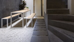 A modern interior with a staircase, a bench, and a potted plant. - On the bed Hostel (Bangkok)
