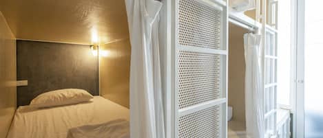 Un dormitorio con cama, cabecera, ventana con cortinas y una pared blanca.