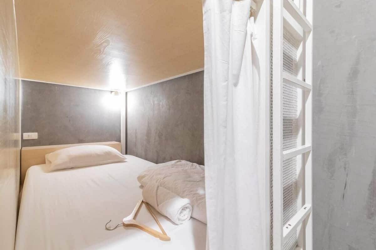 A bedroom with a bed, a hanging towel, and a window with a white curtain.