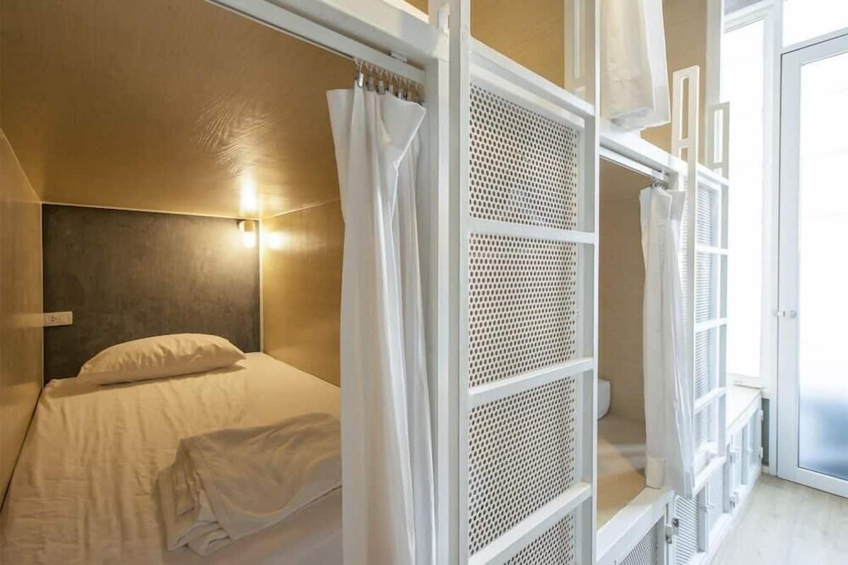 A room with a bed, a white curtain, and a window with a view.
