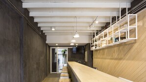 A narrow hallway with a wooden floor, a white stool, and a counter with shelves. - On the bed Hostel (Bangkok)