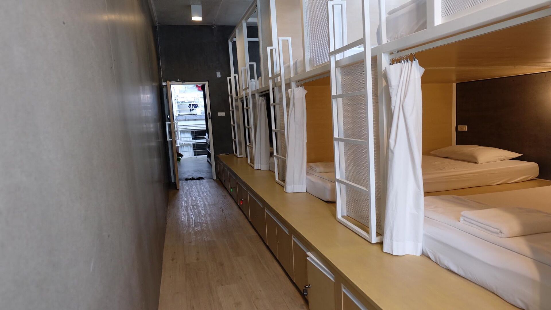 A corridor with bunk beds, a kitchenette, and a bathroom visible in the background.