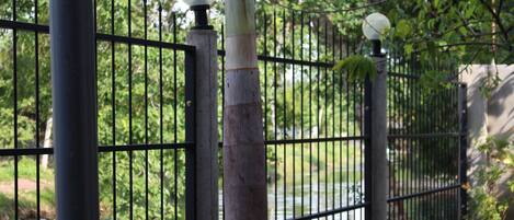A metal fence with a lamp post and a stone base.