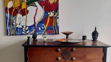 Un meuble en bois avec des tiroirs, une assiette décorative et une statue de Bouddha posée sur le dessus.