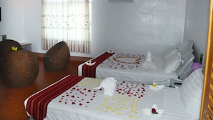 A hotel room with two beds, a large window with curtains, a wall-mounted air conditioner, and a wooden chair. - Hotel Myat Nan Taw (Loikaw)