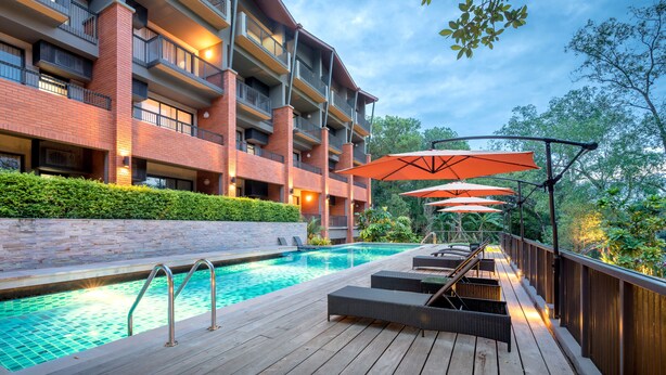 Un hotel con piscina, mobiliario exterior y fachada de ladrillo.