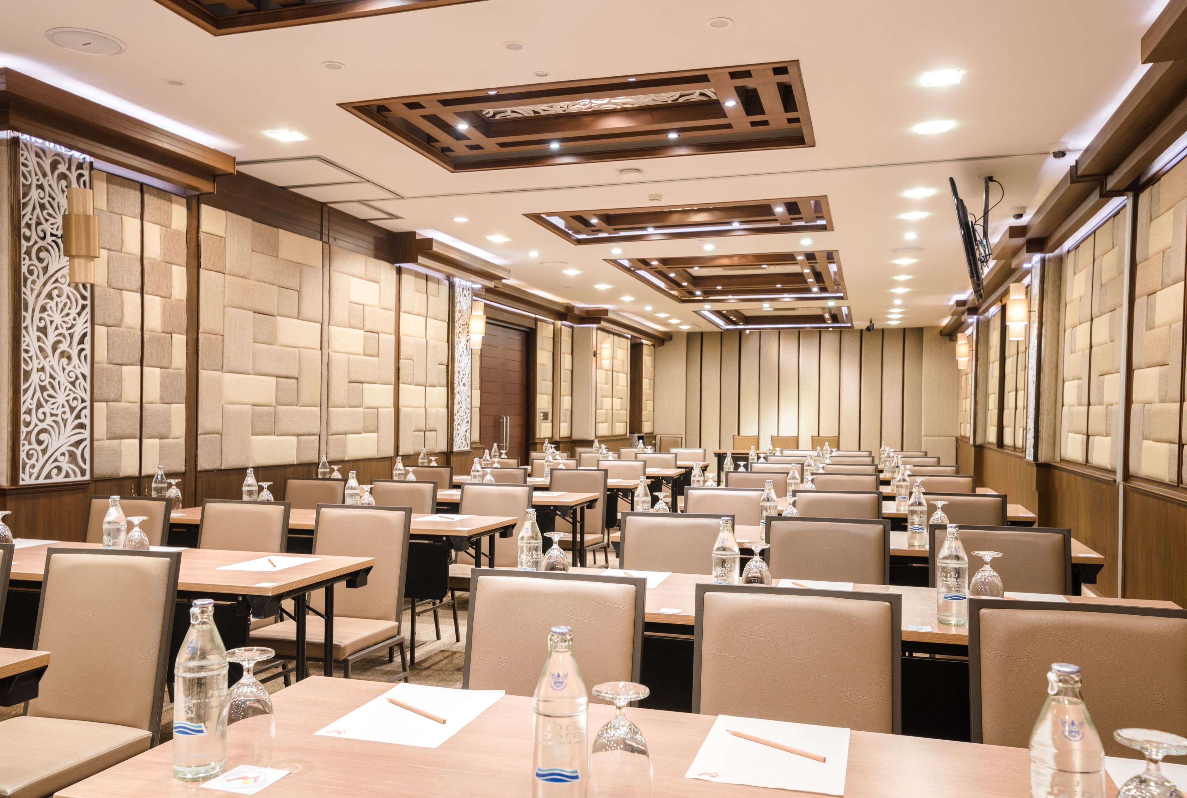 Un salón de conferencias de hotel con varias mesas, sillas y botellas de agua.