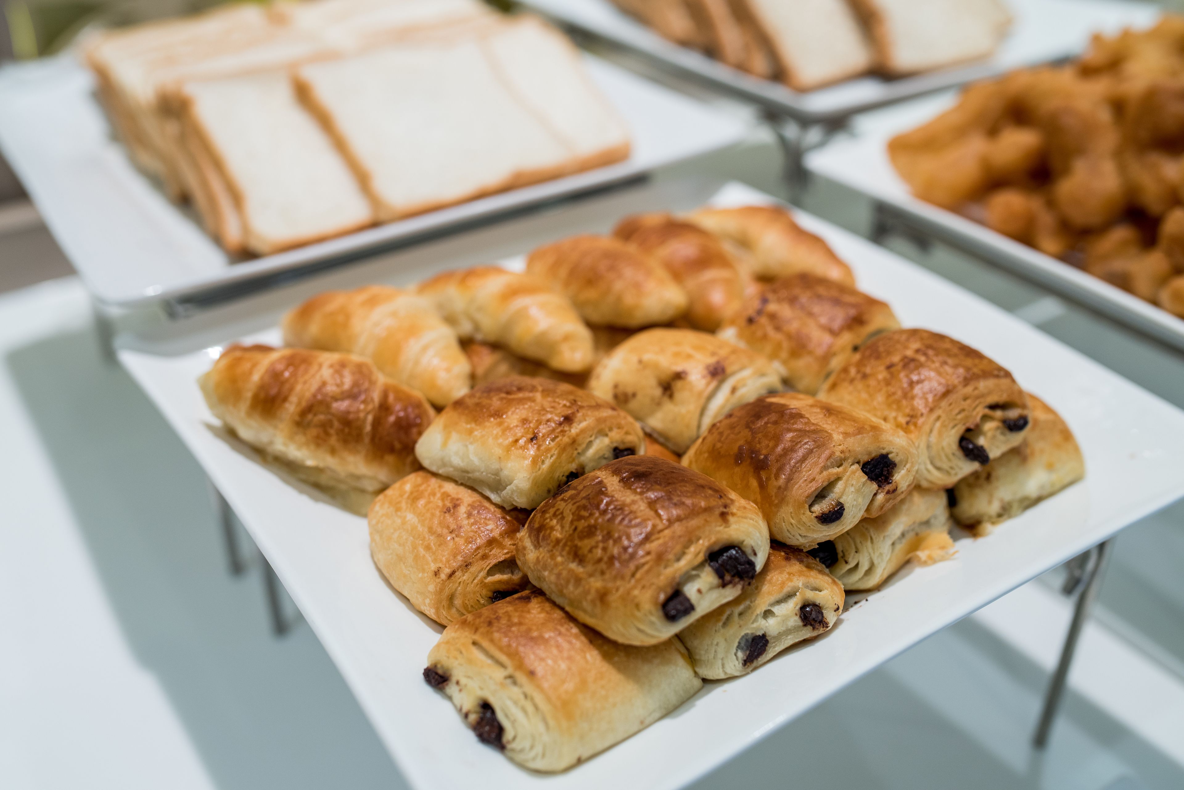 A buffet table with various baked goods including croissants and bread.