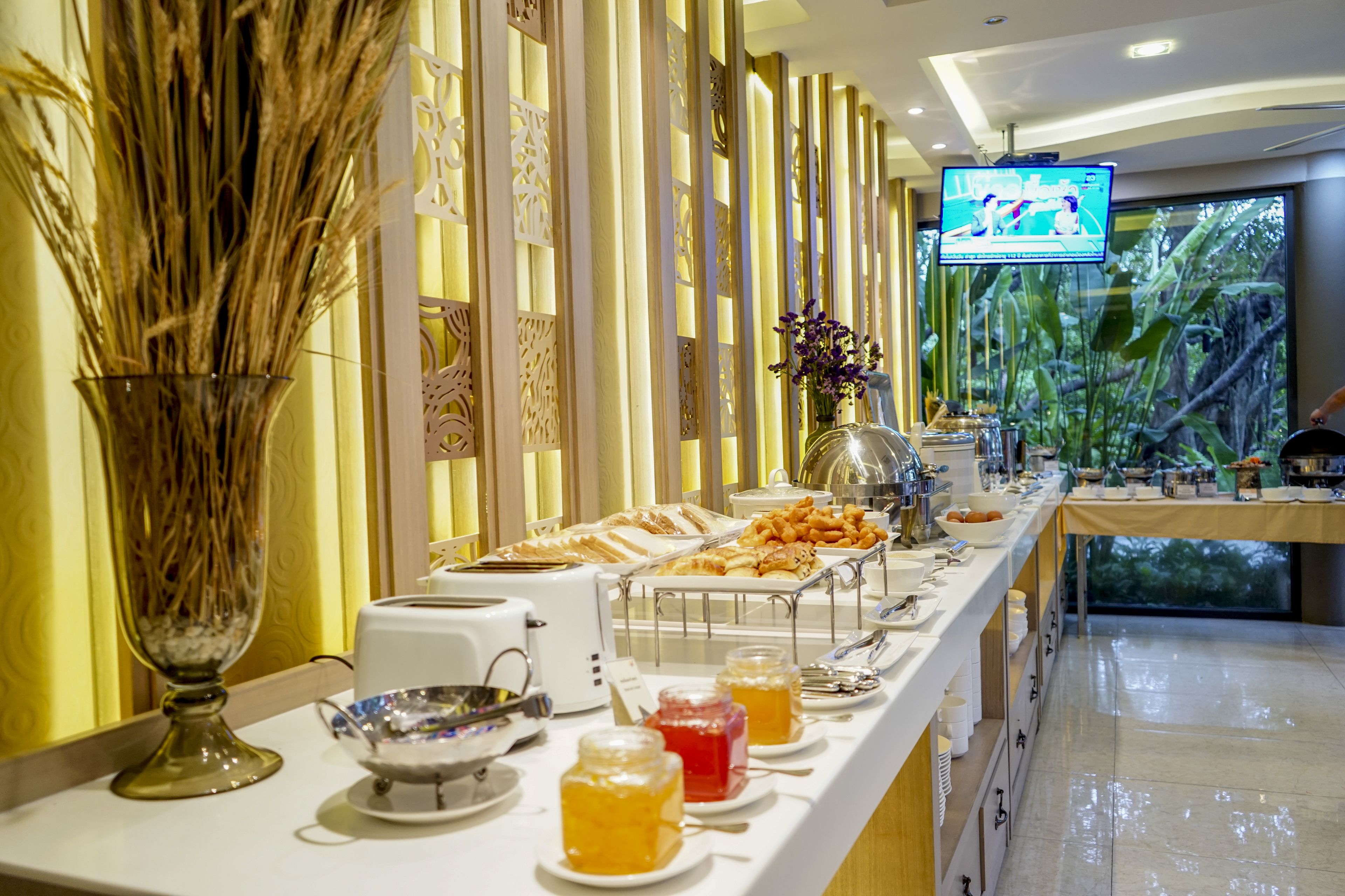 A buffet setup with various food items and a television screen in the background.
