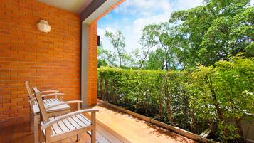 Une terrasse en bois avec un mur en briques et une vue sur un jardin luxuriant.