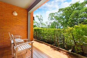 Una terraza de madera con un muro de ladrillo y vistas a un jardín exuberante.