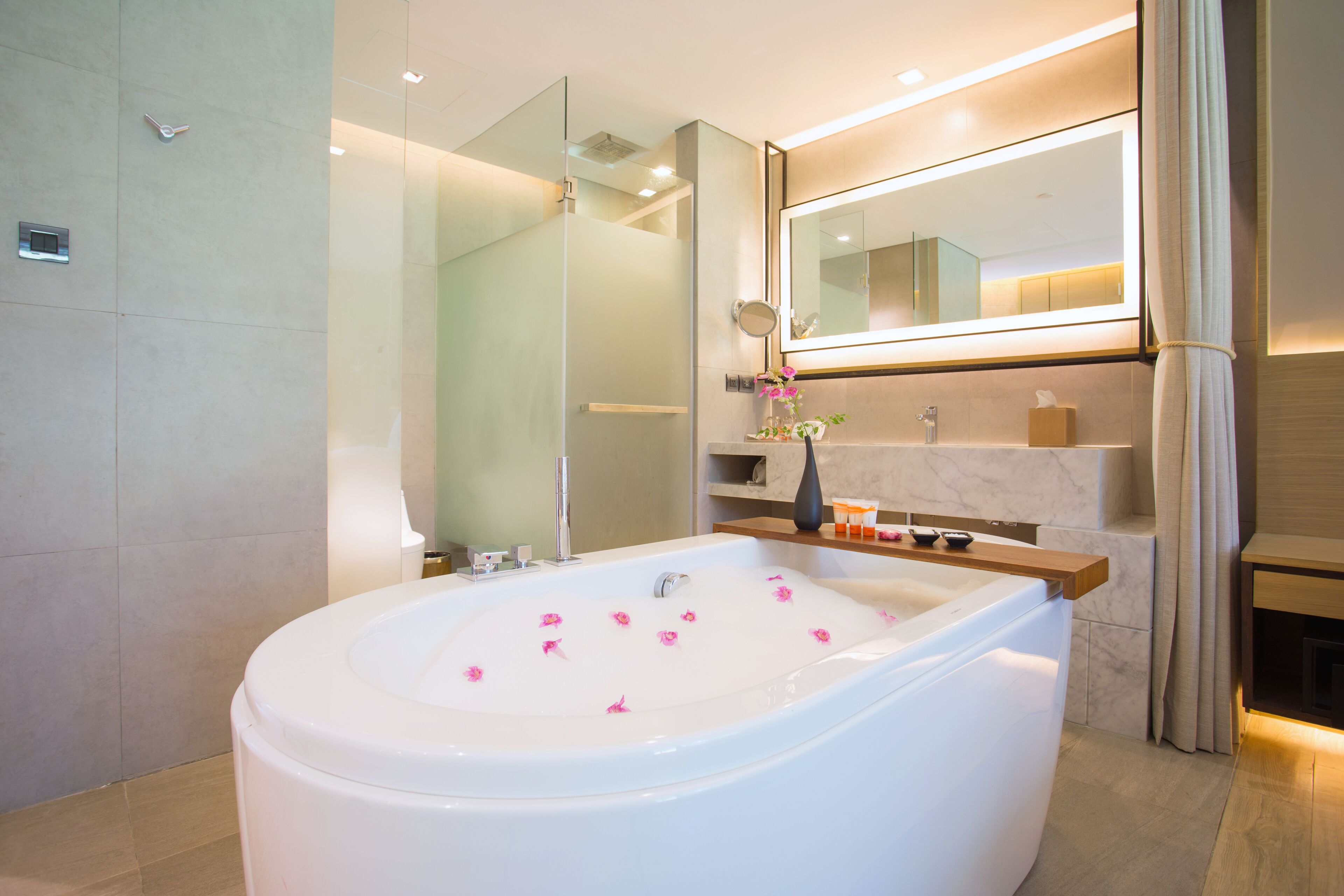 A modern bathroom with a freestanding bathtub, a glass shower enclosure, and a vanity with a mirror.
