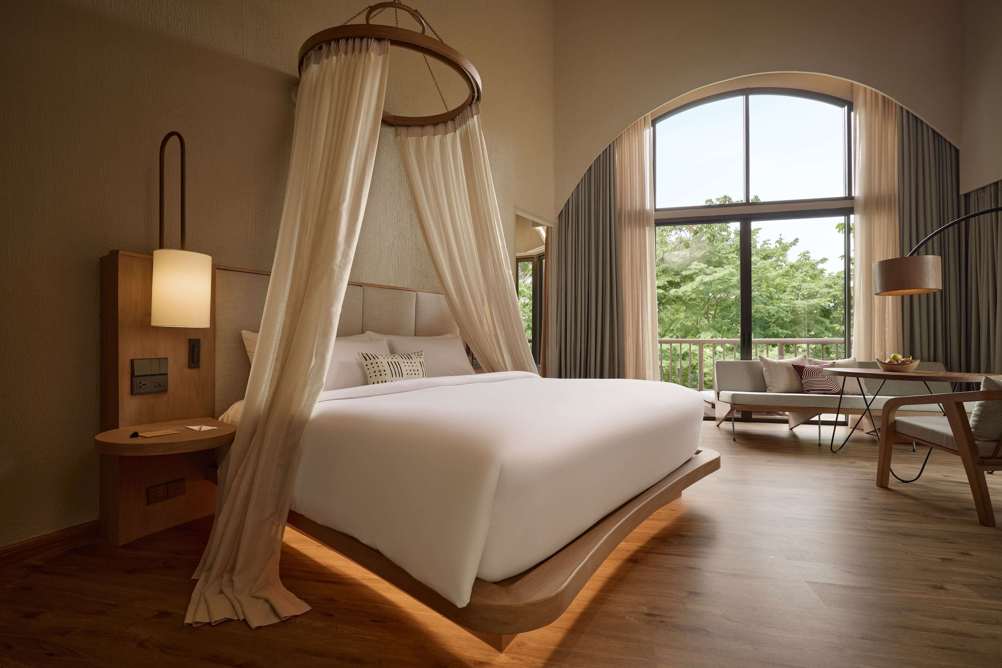 Une chambre spacieuse avec un lit à baldaquin, une table de chevet avec une lampe, un canapé et une table à manger avec des chaises.