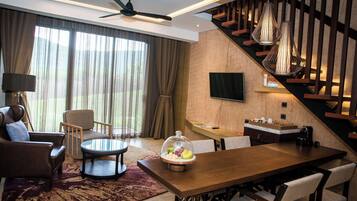 A modern living room with a wooden dining table, leather sofa, and a large window with curtains.