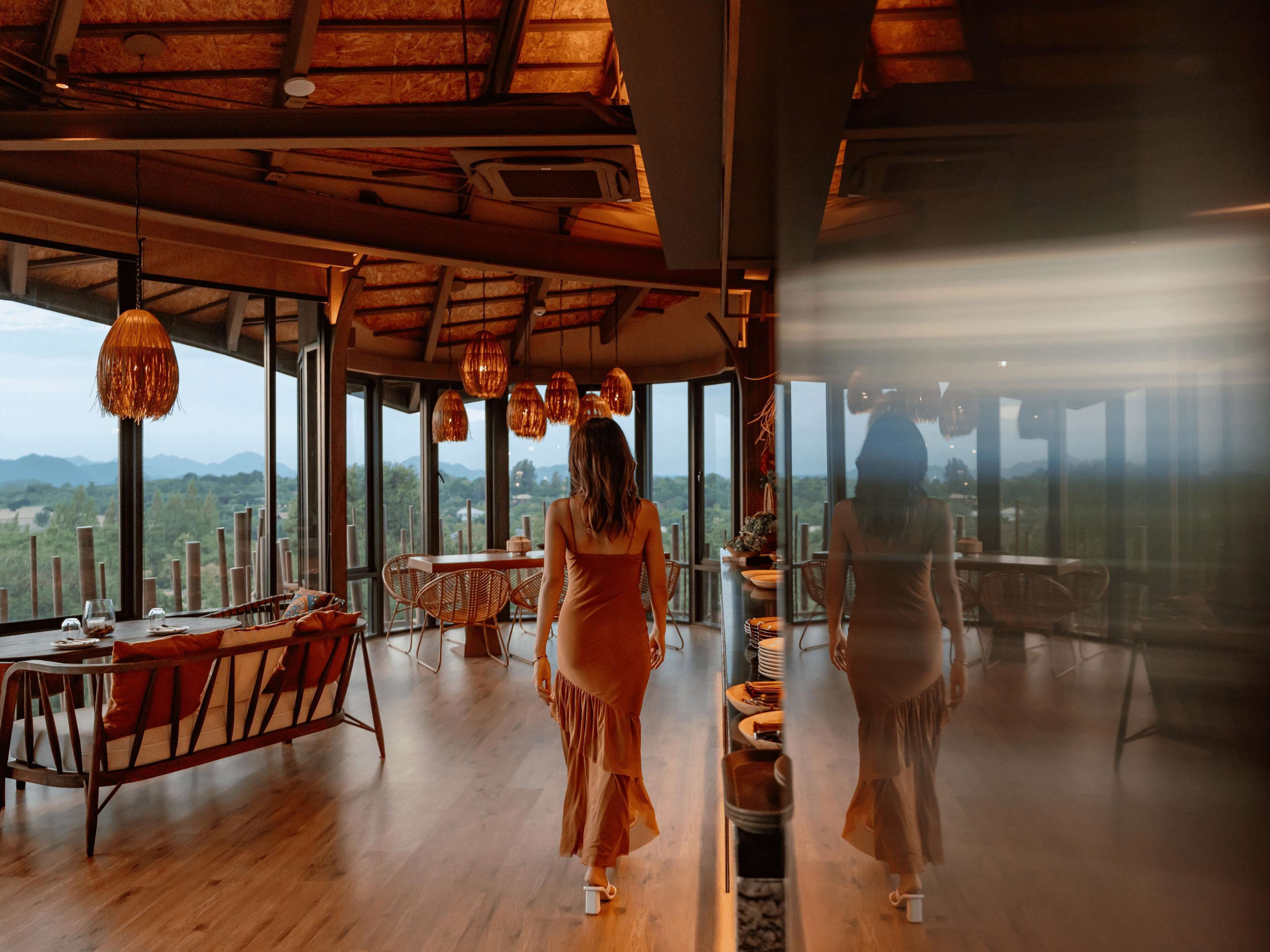 Une pièce spacieuse dotée de grandes fenêtres, d’un plancher en bois et d’un plafond haut avec des luminaires suspendus.
